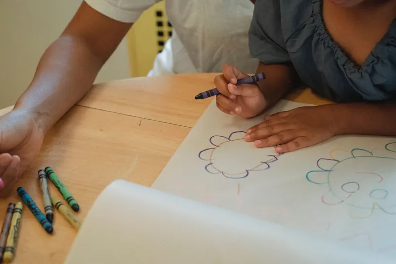 Un adulte et un enfant dessinent aux crayons de cire